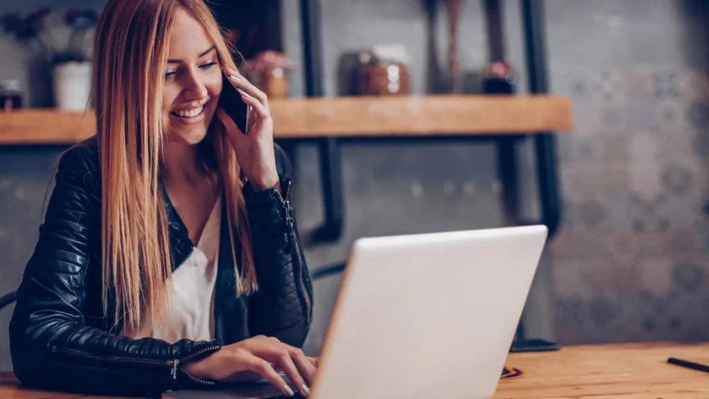 Une femme au téléphone travaille et prospecte ses clients tout en mettant à jour son fichier de prospects.