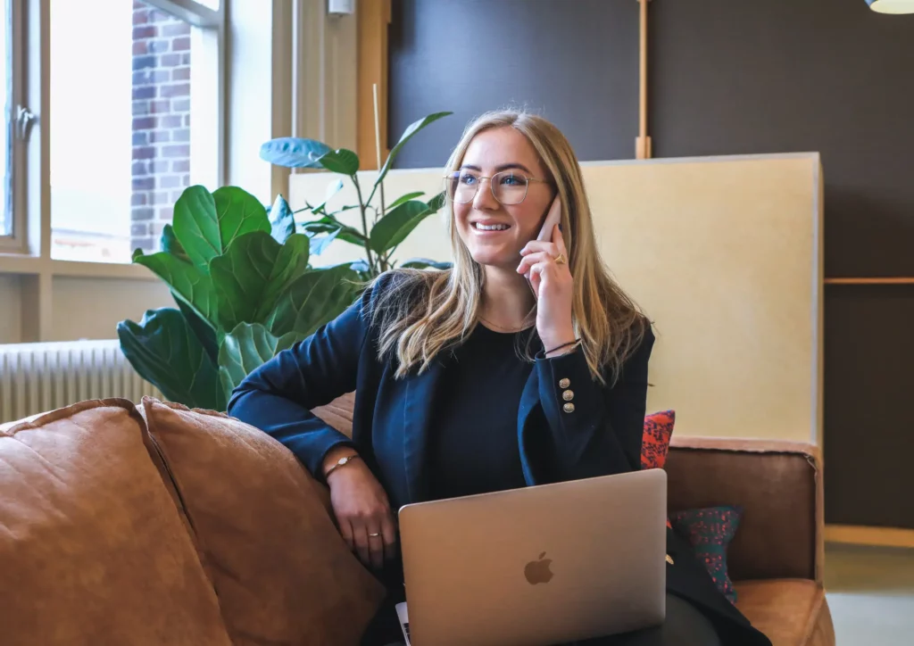 Jeune femme entrepreneure travaillant dans un espace de coworking et assise sur un canapé confortable avec son ordinateur.