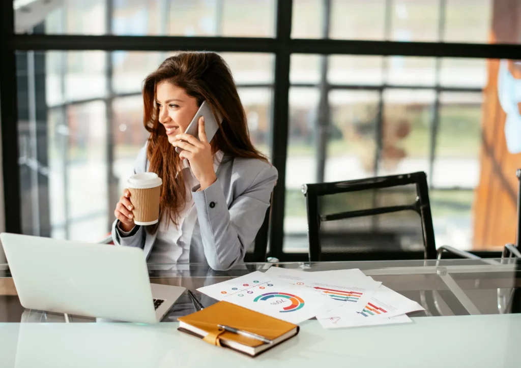 Une businesswoman en plein meeting téléphonique buvant un café.