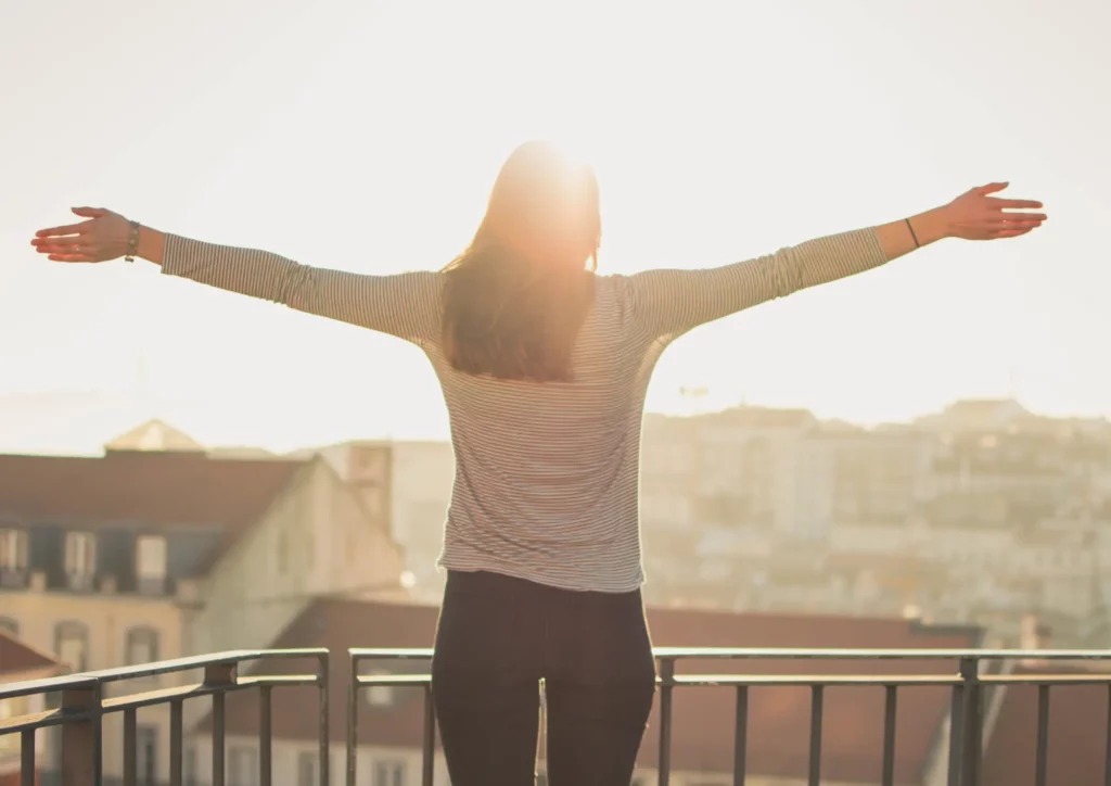 Une femme sur son balcon profitant de son moment perso pour se prélasser au soleil.