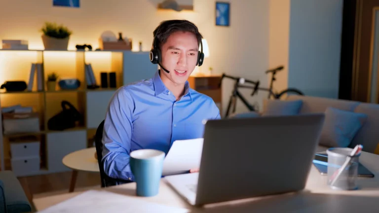 Un homme en télétravail le soir, dans son salon devant son ordinateur.