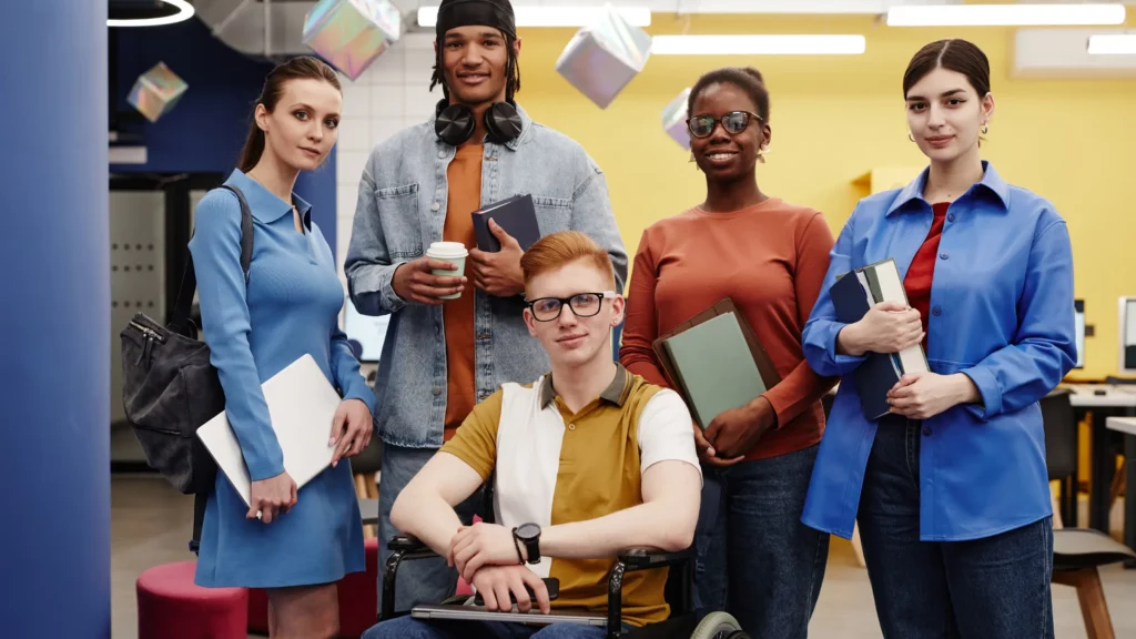 Un groupe d'apprenant ayant chacun des cahier, des ordinateur ou des pochettes dans les bras.