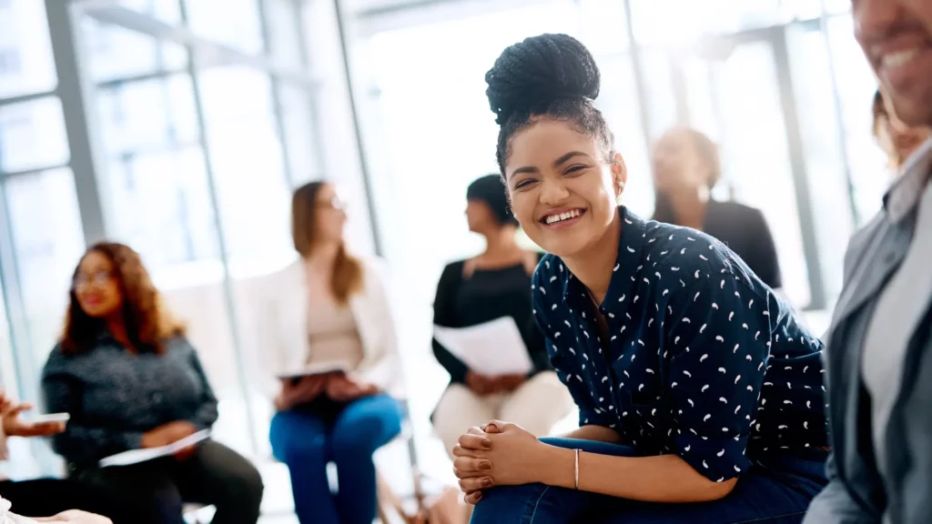 Femme souriante assise de face au milieu d'un groupe de discussion.